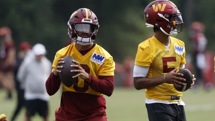 Jul 25, 2024; Ashburn, VA, USA; Washington Commanders quarterbacks Marcus Mariota (0) and Jayden Daniels (5) drop back to pass a ball during drills on day two of Commanders training camp at OrthoVirginia Training Center at Commanders Park. 