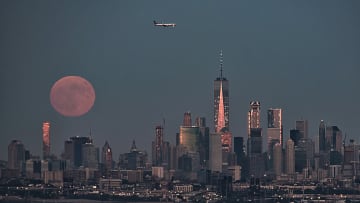 A strawberry moon rising over the Manhattan skyline.