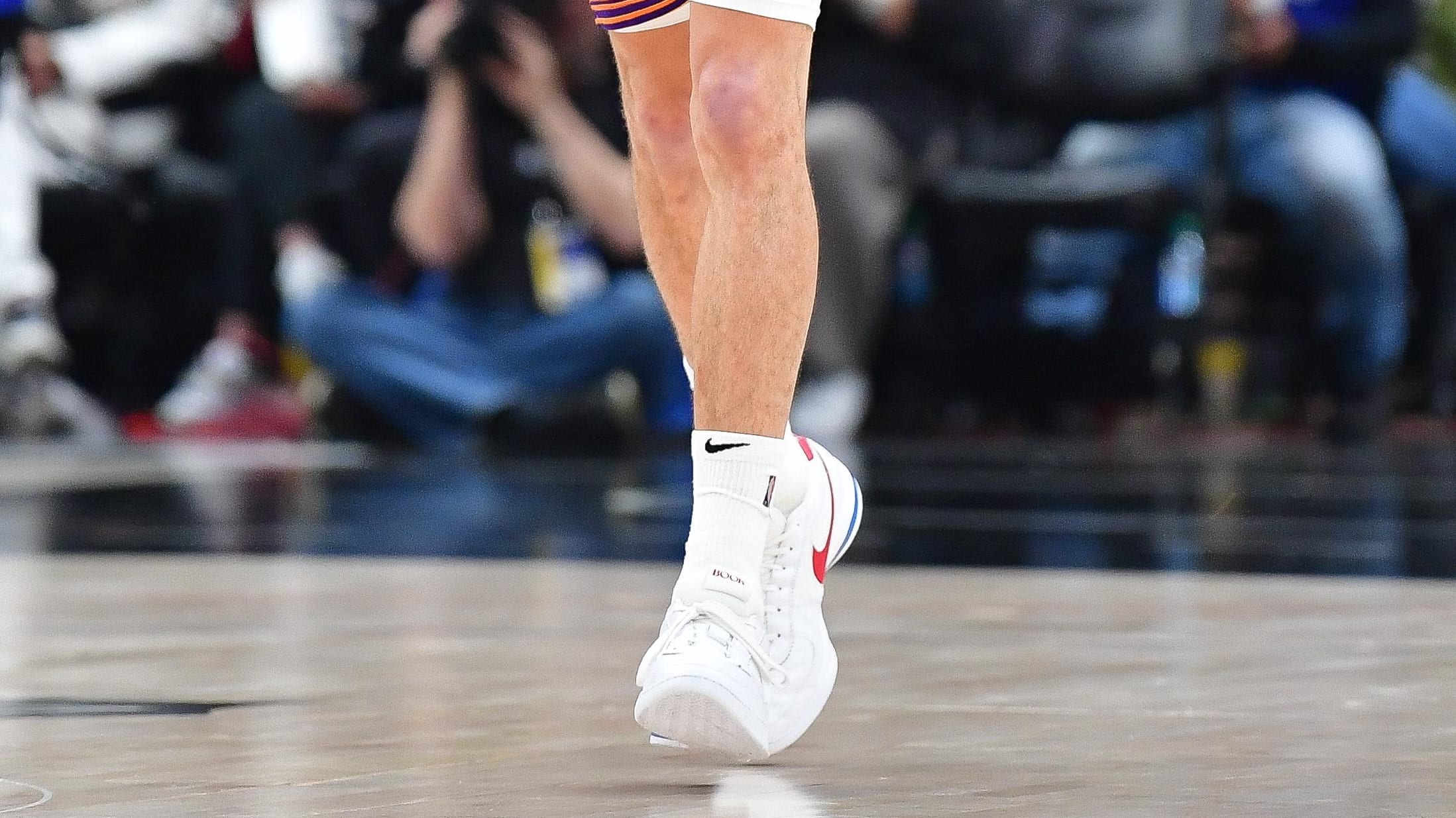 Phoenix Suns guard Devin Booker's white, red, and blue Nike sneakers.