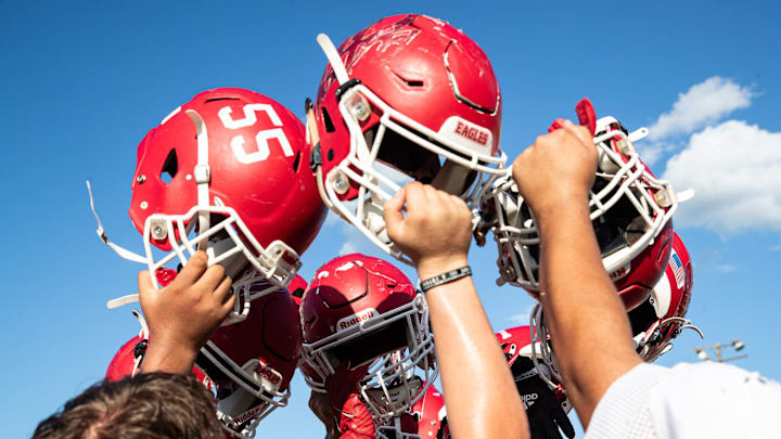 Benavides' six-man football team raises their helmets to break a huddle after practice at the high school in Benavides, Texas.