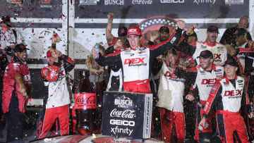 Harrison Burton climbs out of the no. 21 Ford as the crew showers him with Coke Zero Sugar in Victory Lane, Saturday August 24, 2024 after winning the Coke Zero Sugar 400 at Daytona International Speedway.