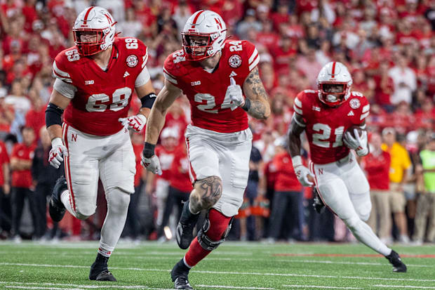 Nebraska offensive lineman Turner Corcoran and tight end Thomas Fidone II lead the way for running back Emmett Johnson.