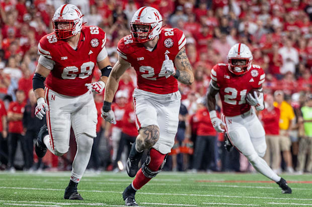 Nebraska offensive lineman Turner Corcoran and tight end Thomas Fidone II lead the way for running back Emmett Johnson.