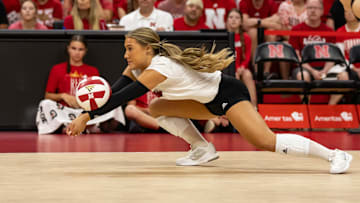 Nebraska volleyball defensive specialist Maisie Boesiger digs a ball while diving to her right wearing a white jersey and black shorts.