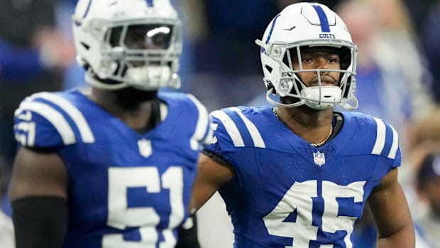 Colts linebacker E.J. Speed (blue jersey; white helmet) stands next to a teammate while waiting for the next play. 