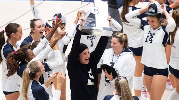 Penn State volleyball head coach Katie Schumacher-Cawley holding up the Big Ten title trophy.