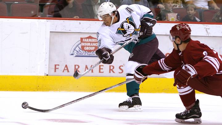 Mar 25, 2006; Glendale, AZ, USA; Anaheim Mighty Ducks right wing (13) Teemu Selanne shoots on goal during the first period against the Phoenix Coyotes defenseman (2) Keith Ballard at Glendale Arena. Mandatory Credit: Rick Scuteri-USA TODAY Sports Copyright Rick Scuteri