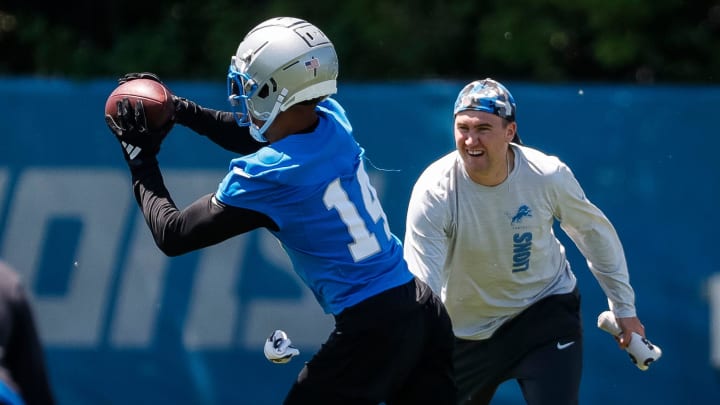 Detroit Lions wide receiver Amon-Ra St. Brown (14) practices as assistant wide receivers coach Seth Ryan watches during OTAs at Detroit Lions headquarters and training facility in Allen Park on Thursday, May 30, 2024.