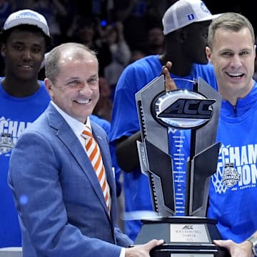 Mar 15, 2025; Charlotte, NC, USA; ACC commissioner Jim Phillips hands the championship trophy to Duke Blue Devils head coach Jon Scheyer after the 2025 ACC Conference Championship game against the Louisville Cardinals at Spectrum Center. Mandatory Credit: Jim Dedmon-Imagn Images