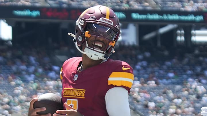 Aug 10, 2024; East Rutherford, New Jersey, USA; Washington Commanders quarterback Jayden Daniels (5) rushes for a touchdown during the first quarter against the New York Jets at MetLife Stadium. Mandatory Credit: Lucas Boland-Imagn Images