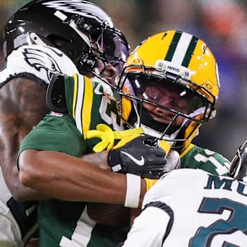 Green Bay Packers wide receiver Dontayvion Wicks (13) is tackled by Quinyon Mitchell and Andrew Mukuba on Monday.
