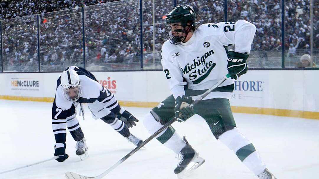 Jan 31, 2026; State College, PA, USA; Michigan State Spartans forward Porter Martone (22) moves the puck against Penn State Nittany Lions defenseman Jackson Smith (7) during the second period at Beaver Stadium. Mandatory Credit: Matthew O'Haren-Imagn Images