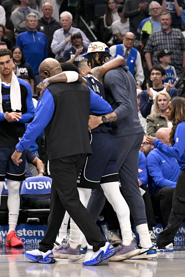 Dallas Mavericks guard Kyrie Irving (11) is helped off the court by forward Anthony Davis