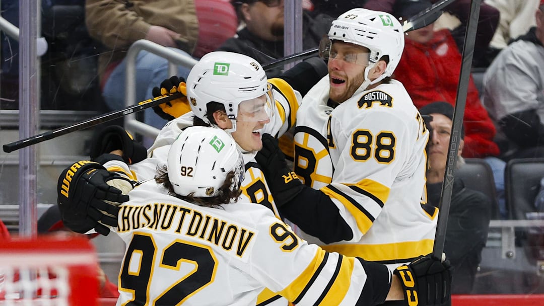 Mar 21, 2026; Detroit, Michigan, USA; Boston Bruins defenseman Nikita Zadorov (91) celebrates with right wing David Pastrnak (88) and center Marat Khusnutdinov (92) after scoring a goal in the third period against the Detroit Red Wings at Little Caesars Arena. Mandatory Credit: Brian Bradshaw Sevald-Imagn Images