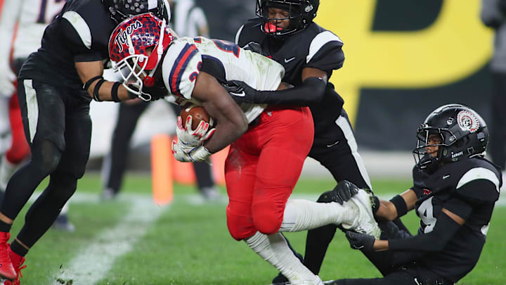 Aliquippa's QaLil Goode (14), Gavin Wilcox (13), and Arison Walker (15) attempt to hold back McKeesport's Kemon Spell (20)