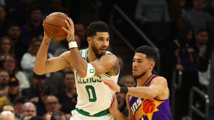 Dec 7, 2022; Phoenix, Arizona, USA; Boston Celtics forward Jayson Tatum (0) controls the ball against Phoenix Suns guard Devin Booker (1) in the first half at Footprint Center. Mandatory Credit: Mark J. Rebilas-USA TODAY Sports