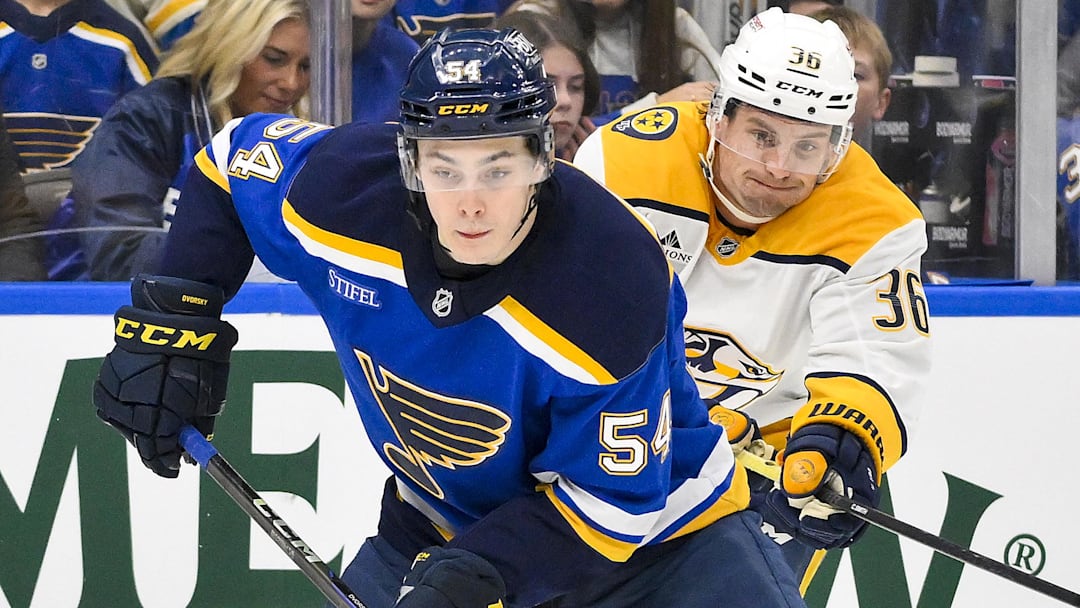 Mar 23, 2025; St. Louis, Missouri, USA;  St. Louis Blues center Dalibor Dvorsky (54) controls the puck as Nashville Predators left wing Cole Smith (36) defends during the second period at Enterprise Center. Mandatory Credit: Jeff Curry-Imagn Images