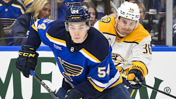 Mar 23, 2025; St. Louis, Missouri, USA;  St. Louis Blues center Dalibor Dvorsky (54) controls the puck as Nashville Predators left wing Cole Smith (36) defends during the second period at Enterprise Center. Mandatory Credit: Jeff Curry-Imagn Images