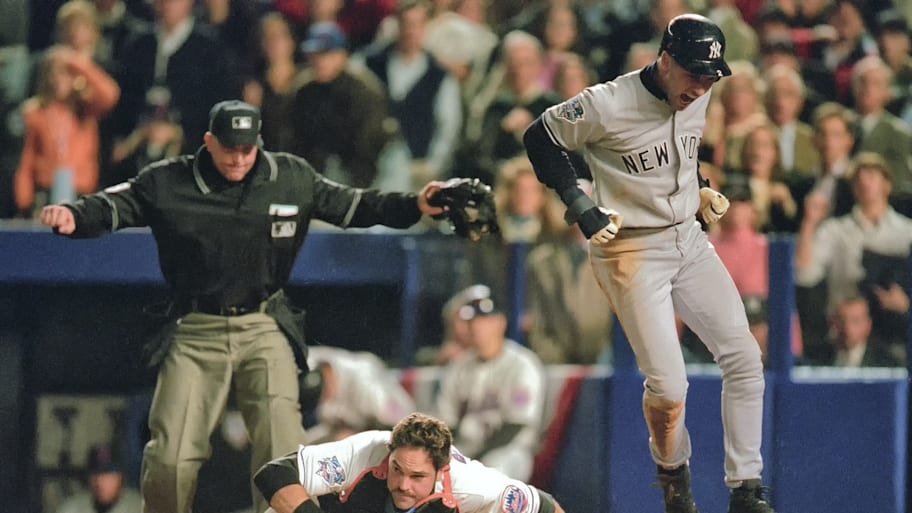 Yankees’ Derek Jeter, right, victorious after scoring run vs Mets’ Mike Piazza during 2000 World Series Game 3.