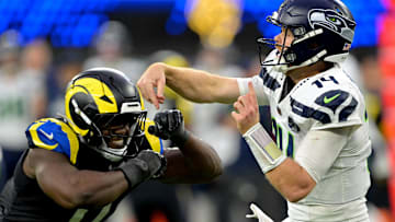 Nov 16, 2025; Inglewood, California, USA; Seattle Seahawks quarterback Sam Darnold (14) is pressured by Los Angeles Rams linebacker Byron Young (0) at SoFi Stadium. 