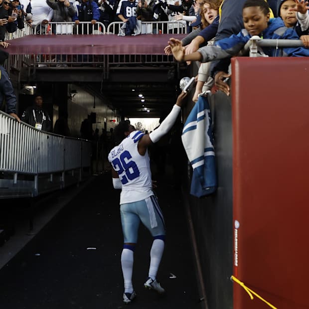 Dallas Cowboys cornerback DaRon Bland hands a piece of his equipment to a fan after a game against the Washington Commanders