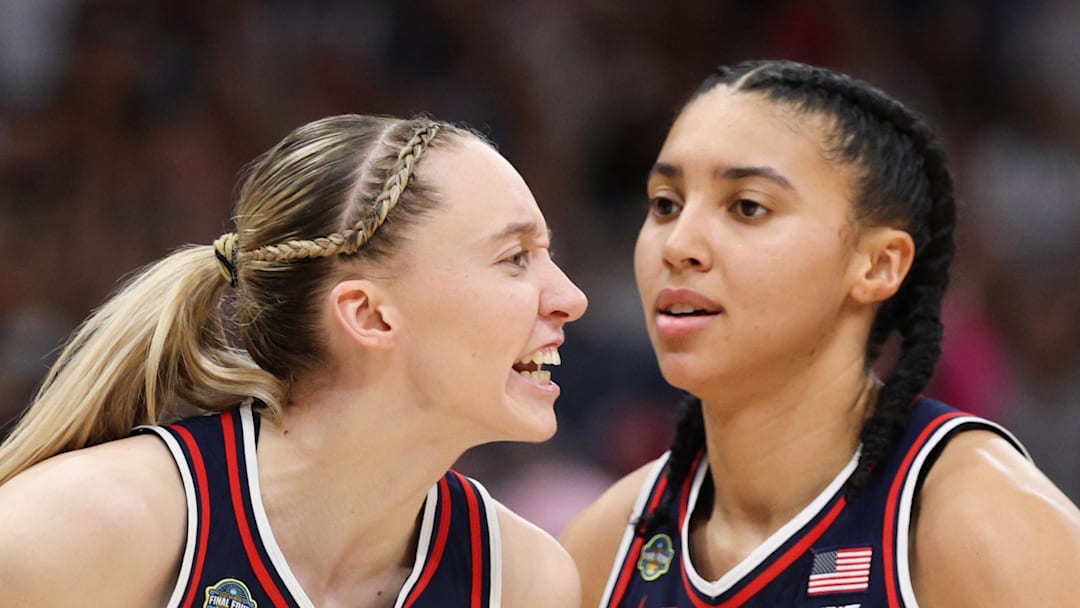 Connecticut Huskies guard Paige Bueckers reacts with teammates guard Ashlynn Shade and guard Azzi Fudd.