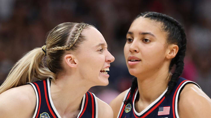 Connecticut Huskies guard Paige Bueckers reacts with teammates guard Ashlynn Shade and guard Azzi Fudd.