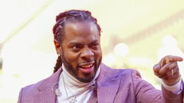 Commentator Richard Sherman signals to fans