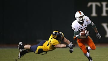 Dec. 27, 2008; San Francisco, CA, USA; Miami Hurricanes running back Lee Chambers (32) eludes the grasp of California Golden Bears linebacker Zack Follett (56) during the fourth quarter in the 2008 Emerald Bowl at AT&T Park in San Francisco, CA. The Golden Bears defeated the Hurricanes 24-17. Mandatory Credit: Cary Edmondson-Imagn Images