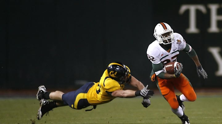 Dec. 27, 2008; San Francisco, CA, USA; Miami Hurricanes running back Lee Chambers (32) eludes the grasp of California Golden Bears linebacker Zack Follett (56) during the fourth quarter in the 2008 Emerald Bowl at AT&T Park in San Francisco, CA. The Golden Bears defeated the Hurricanes 24-17. Mandatory Credit: Cary Edmondson-Imagn Images