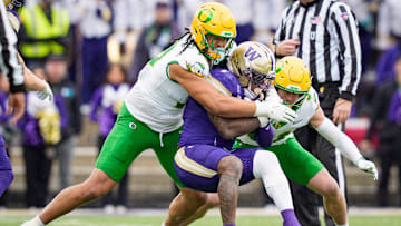 Oregon outside linebacker Matayo Uiagalelei, left, and Oregon defensive back Dillon Thieneman bring down Washington running back Jonah Coleman as the Oregon Ducks take on the Washington Huskies on Nov. 29, 2025, at Husky Stadium in Seattle, Washington.