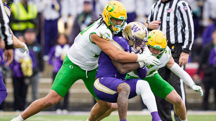 Oregon outside linebacker Matayo Uiagalelei, left, and Oregon defensive back Dillon Thieneman bring down Washington running back Jonah Coleman as the Oregon Ducks take on the Washington Huskies on Nov. 29, 2025, at Husky Stadium in Seattle, Washington.