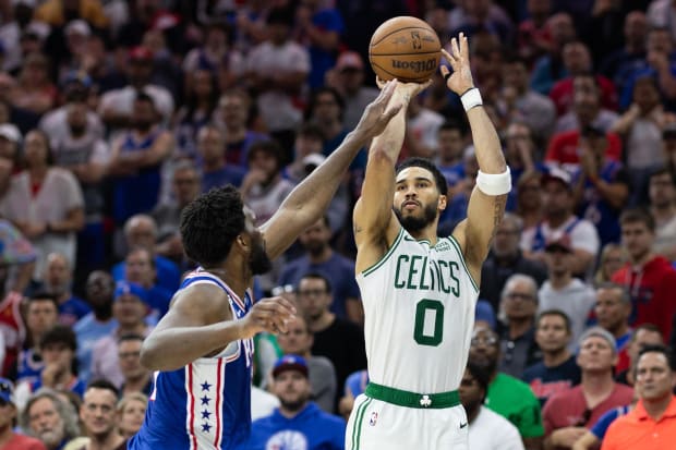 Boston Celtics forward Jayson Tatum (0) shoots the ball past Philadelphia 76ers center Joel Embiid (21).