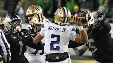 The Oregon defense including Jordan Burch, left, and Derrick Harmon, right, hurry Washington quarterback Demond Williams Jr.during the second at Autzen Stadium in Eugene.