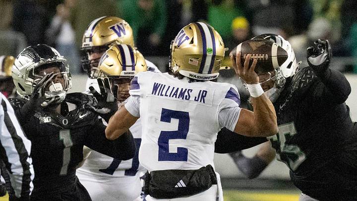 The Oregon defense including Jordan Burch, left, and Derrick Harmon, right, hurry Washington quarterback Demond Williams Jr.during the second at Autzen Stadium in Eugene.