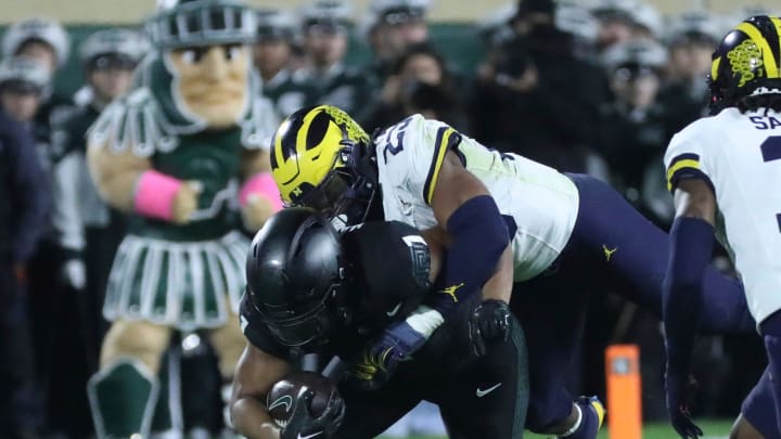 Michigan Wolverines linebacker Michael Barrett (23) tackles Michigan State Spartans defensive back Jaden Mangham (1) during second-half action at Spartan Stadium in East Lansing on Saturday, Oct. 21, 2023.