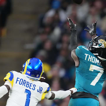 Oct 19, 2025; London, United Kingdom; Jacksonville Jaguars wide receiver Brian Thomas Jr. (7) reaches for the ball against Los Angeles Rams cornerback Emmanuel Forbes Jr. (1) during the second half of an NFL International Series game at Wembley Stadium. 