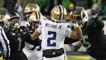 The Oregon defense including Jordan Burch, left, and Derrick Harmon, right, hurry Washington quarterback Demond Williams Jr.during the second at Autzen Stadium in Eugene.