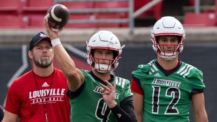 Louisville quarterback Tyler Shough (9) runs a drill during their practice while Brady Allen (12) and offensive coordinator Brian Brohm (left) watches.