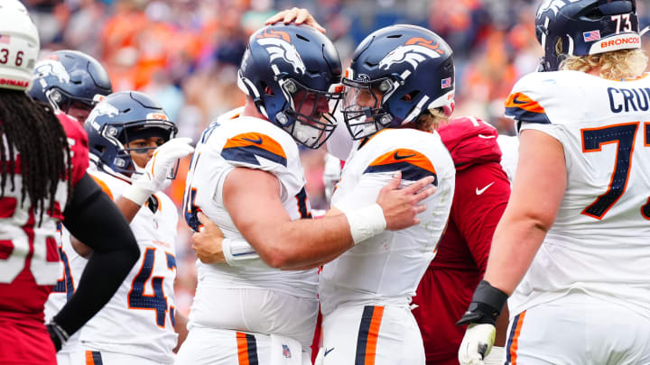 Aug 25, 2024; Denver, Colorado, USA; Denver Broncos quarterback Zach Wilson (4) celebrates his rushing touchdown with center Alex Forsyth (54) in the second half at Empower Field at Mile High. 