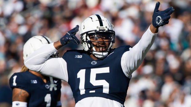 A Penn State football player lifts his arms and points to the crowd to celebrate a play.