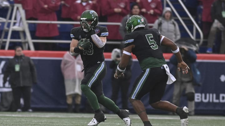 Dec 27, 2023; Annapolis, MD, USA;  Tulane Green Wave linebacker Tyler Grubbs (13) picks up a fumble for a touchdown during the first quarter against the Virginia Tech Hokies at Navy-Marine Corps Memorial Stadium. Mandatory Credit: Tommy Gilligan-USA TODAY Sports