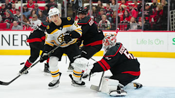 Mar 6, 2025; Raleigh, North Carolina, USA;  Carolina Hurricanes goaltender Pyotr Kochetkov (52) and Boston Bruins center Matthew Poitras (51) watch the puck during the second period at Lenovo Center. Mandatory Credit: James Guillory-Imagn Images