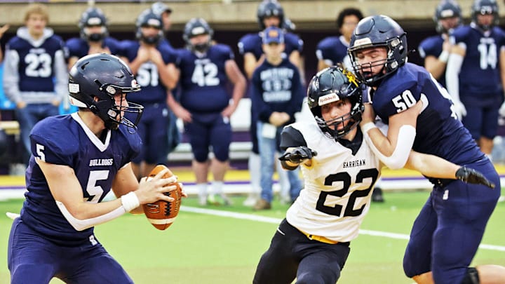 Bedford senior quarterback Conner Nally (5) is forced to rush his pass as the Bishop Garrigan (Algona) Golden Bears compete against the Bedford Bulldogs for the Eight-Player championship on Thursday, November 16, 2023 at the UNI-Dome in Cedar Falls.