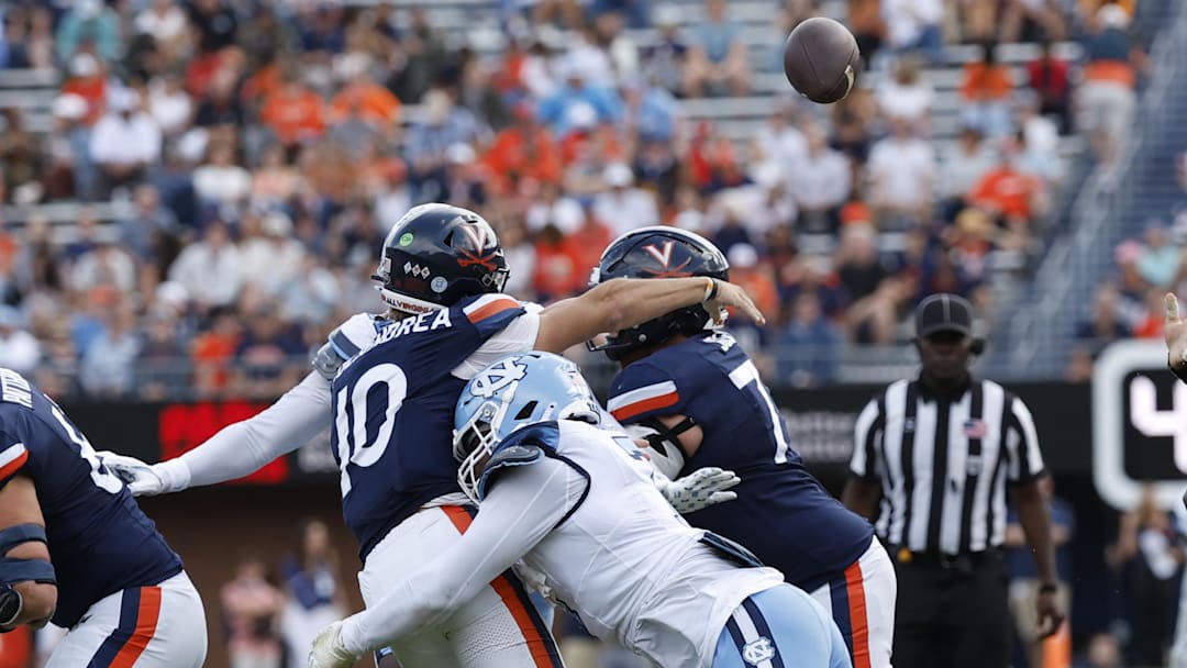 Oct 26, 2024; Charlottesville, Virginia, USA; Virginia Cavaliers quarterback Anthony Colandrea (10) passes the ball while being hit by North Carolina Tar Heels defensive end Kaimon Rucker (7) during the first half at Scott Stadium. Mandatory Credit: Geoff Burke-Imagn Images