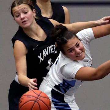 Xavier High School's Hailey Hafner (2) battles for a rebound against Menasha High School's Rayanna Jenkins (4) during their girls basketball game Thursday, December 11, 2025, in Menasha, Wisconsin. Xavier won 49-39.