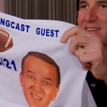 Eli Manning presents a present to Charles Barkley, who won't wear it. 