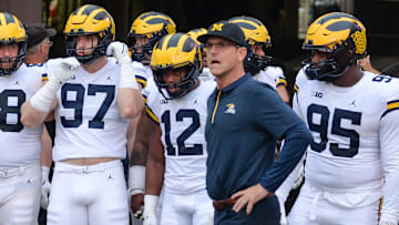 Head coach Jim Harbaugh of the Michigan Wolverines waits with offensive lineman Andrew Vastardis #68 and defensive end Aidan Hutchinson #97 and quarterback Cade McNamara #12 and defensive lineman Donovan Jeter #95 to take the field against the Nebraska Cornhuskers at Memorial Stadium on October 9, 2021 in Lincoln, Nebraska