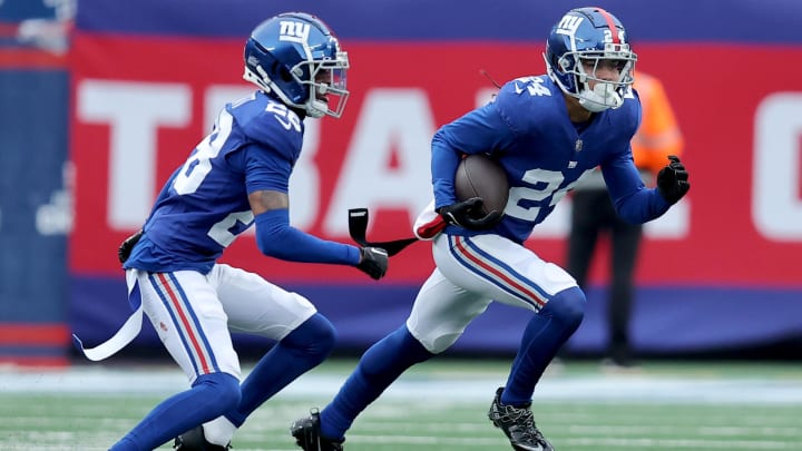 Dec 31, 2023; East Rutherford, New Jersey, USA; New York Giants safety Dane Belton (24) runs back an interception against the Los Angeles Rams with cornerback Cor'Dale Flott (28) during the second quarter at MetLife Stadium.  