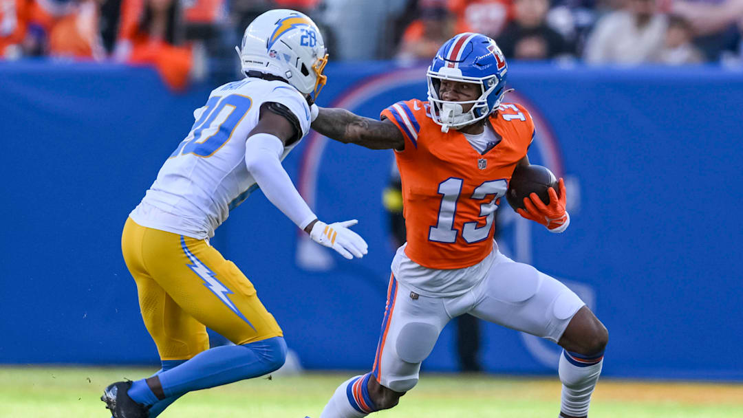 DENVER, CO - JANUARY 04: Pat Bryant 13 of the Denver Broncos, runs the ball and gives the stiff arm to Hassan Haskins 28 of the Los Angeles Chargers, during a game between the Los Angeles Chargers and the Denver Broncos at Empower Field at Mile High in Denver, CO on January 04, 2026.